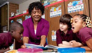 adult woman helping children learn how to read